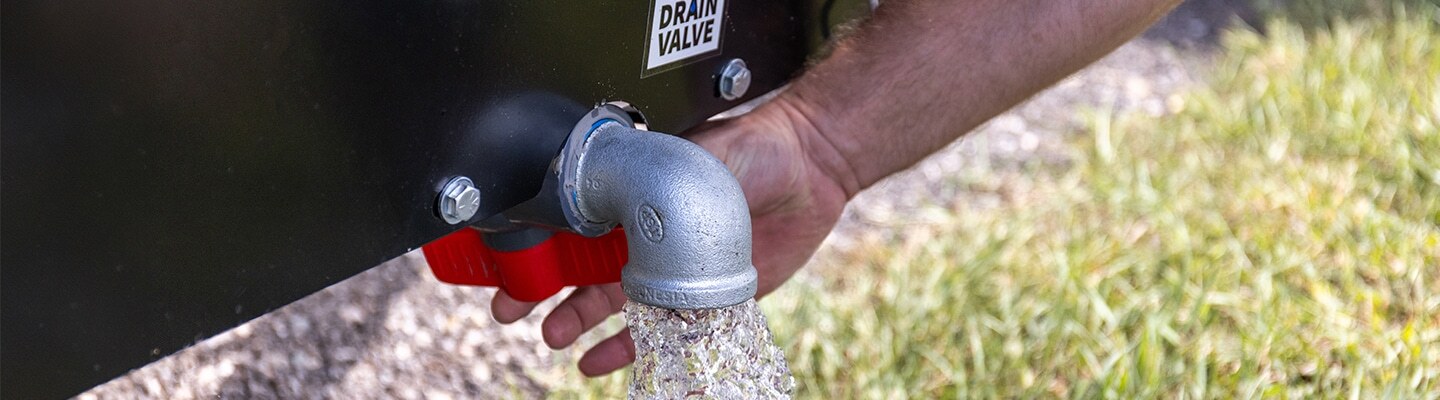 Hand turning a valve to drain an ABI Attachments Compact Water Trailer