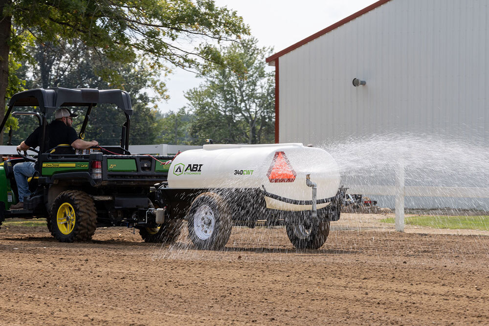 ABI Attachments 340 Gallon Compact Water Trailer spraying water on ground while being pulled by a UTV