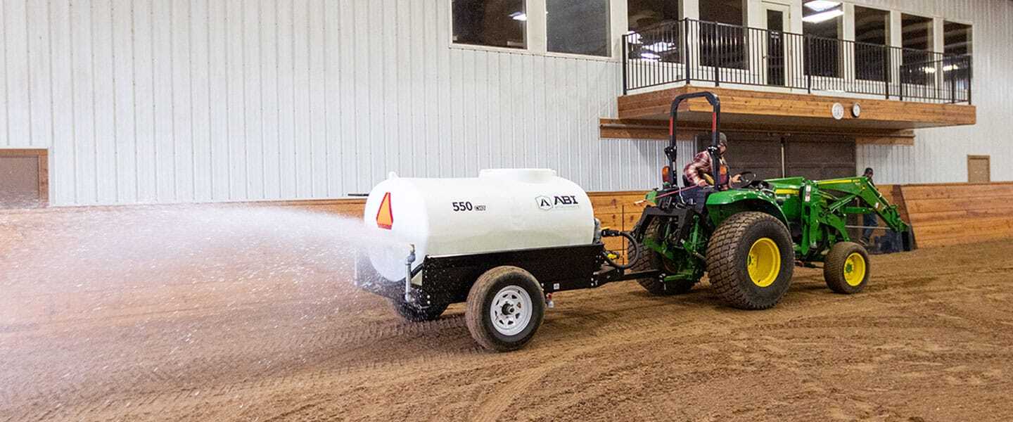 ABI Attachments 550 Gallon Compact Water Trailer spreading water on a synthetic arena