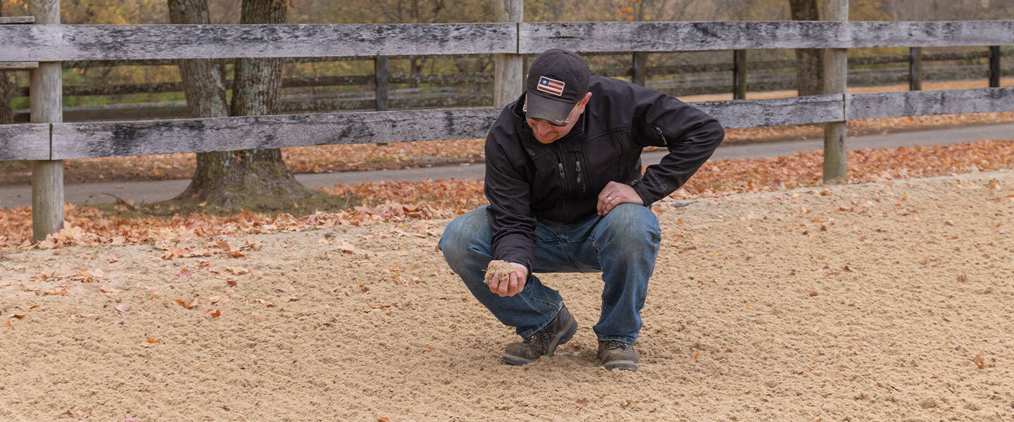 Man checking synthetic footing arena making sure its getting taken care of.