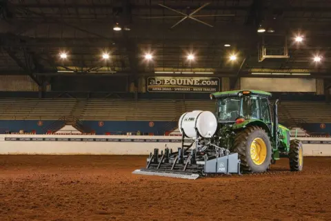 Speedmaster being displayed in a indoor arena. The sign says 'abiequine.com - Arena Drags - Spreaders - Water Trailers'