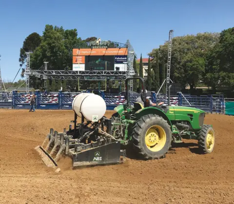 Speedmaster grooming the ‘Cal Pony’ arena while attached to a green tractor, leveling and preparing the footing.