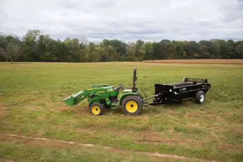 John Deere Tractor pull behind 125 PTO Manure Spreader being displayed.