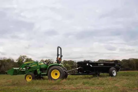 John Deere Tractor pull behind 125 PTO Manure Spreader for farms being displayed.