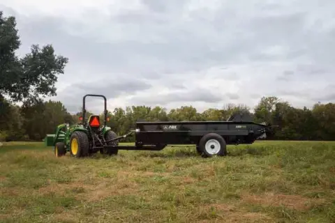 125 PTO pull behind Manure Spreader in a pasture being displayed.