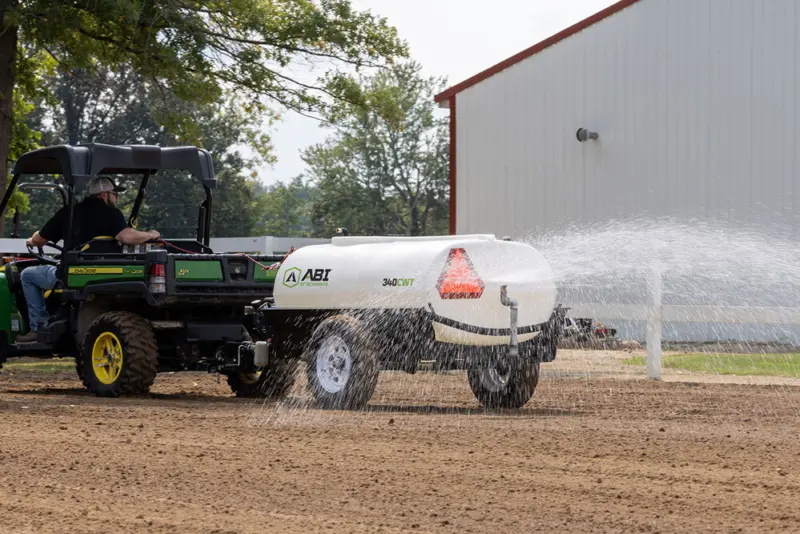 ABI Attachments 340 Gallon Compact Water Trailer spraying water on ground while being pulled by a UTV