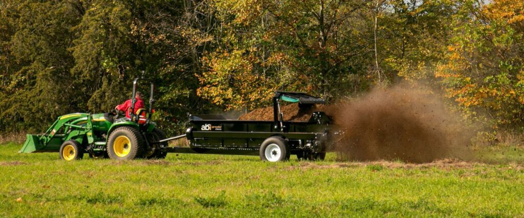 ABI Attachments 185 Cubic Foot PTO Driven Manure Spreader spreading manure in a pasture