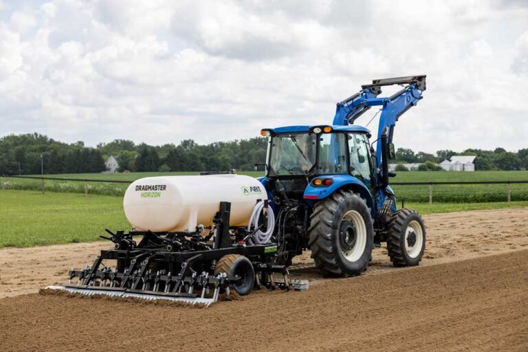 Dragmaster Horizon in use on soil, while attached to a blue tractor.