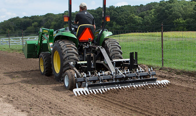 TR3 is being used in the soil/dirt while being attached to a large green tractor.