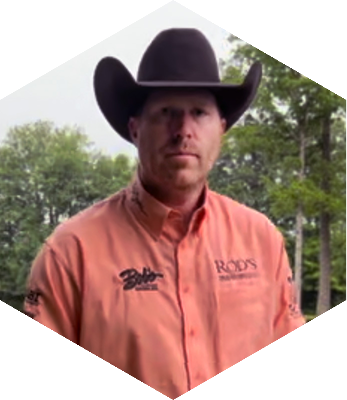 Brandon Brant in a orange collared shirt with a cowboy hat on.