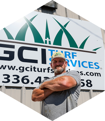 Pete Denny, owner of 'GCI Turf Services', crosses his arms looking straight onto the camera.