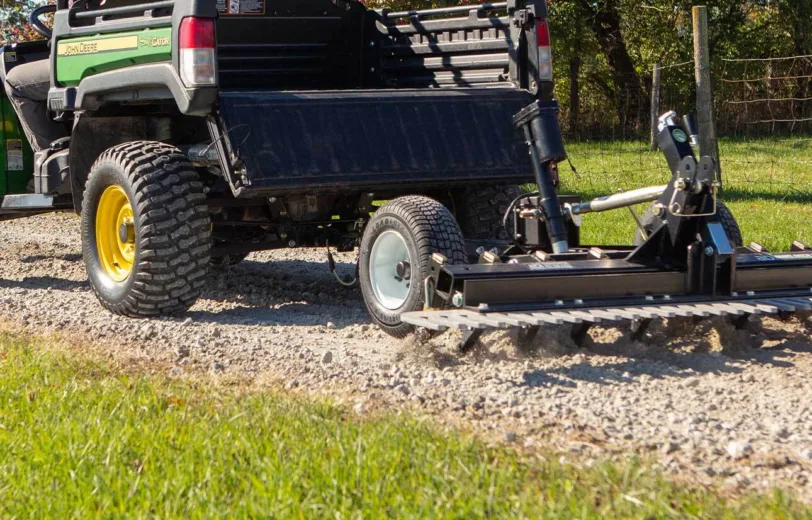 ABI Attachments' driveway grader being pulled by a ATV on gravel.