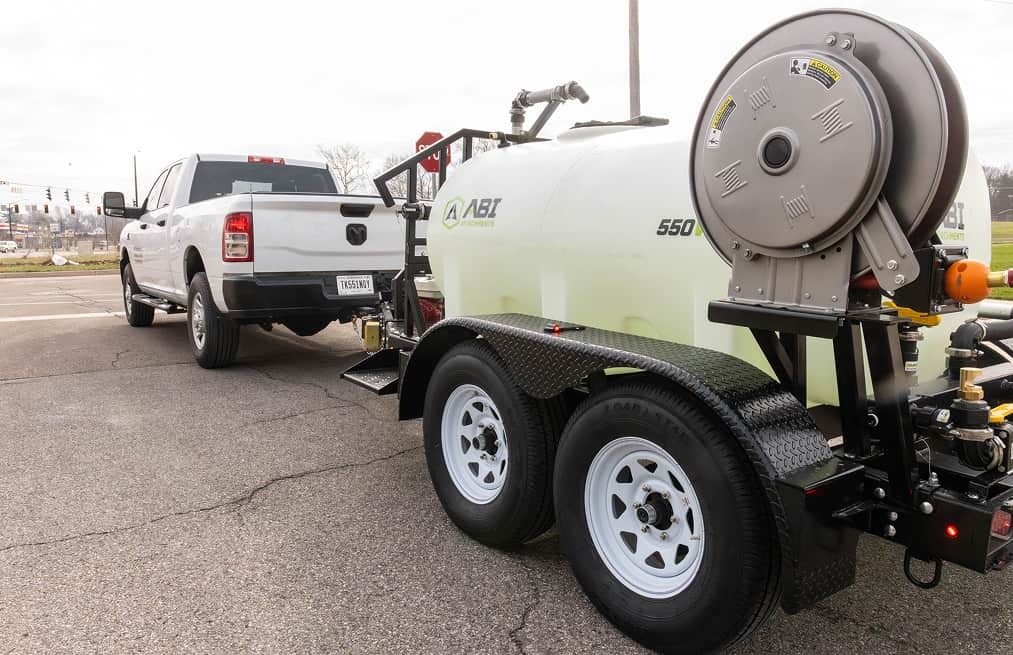 Rear angle view of the ABI 550 DOT Pro Water Trailer hitched to a pickup truck